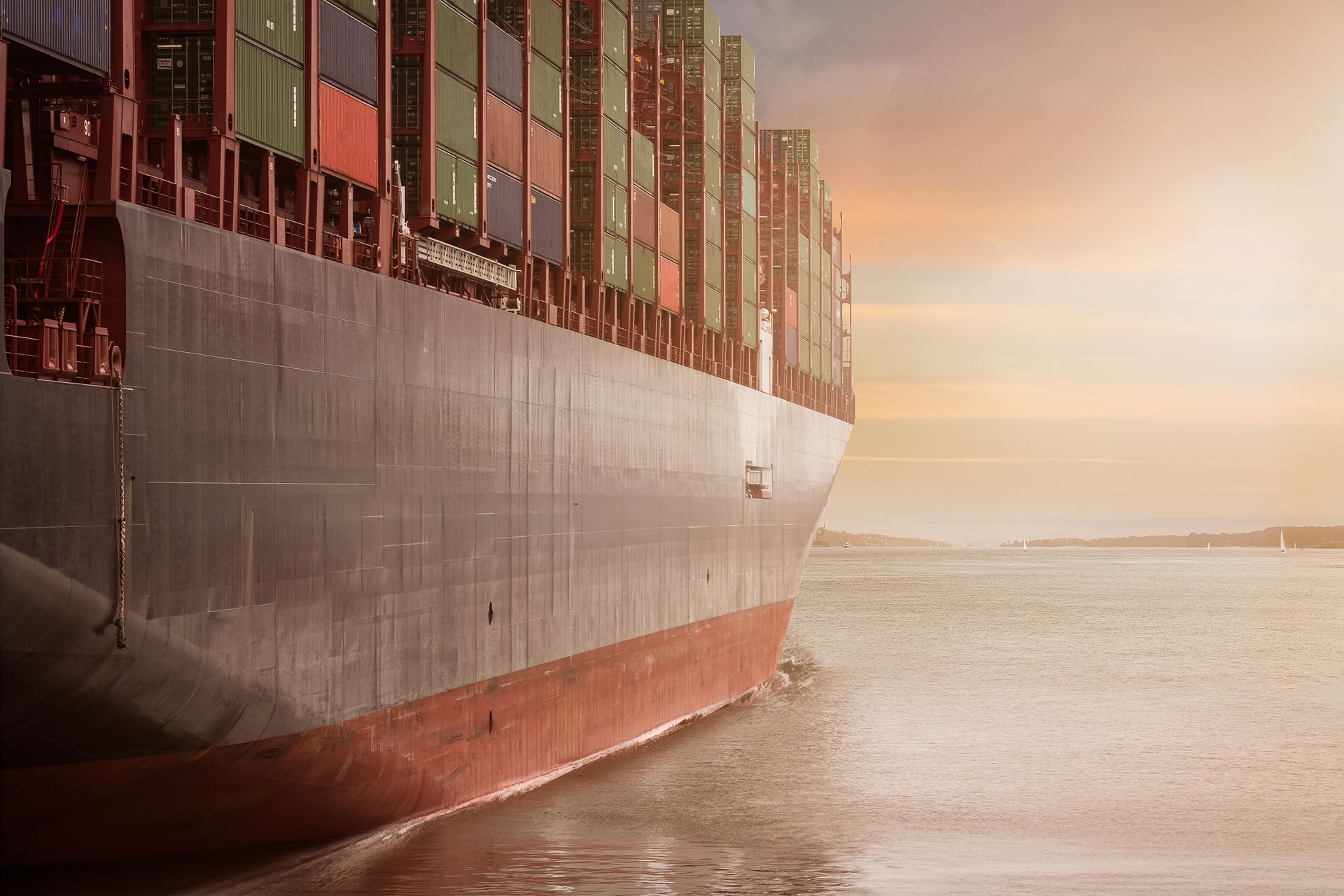 Container ship loaded with cargo sailing into a golden sunset